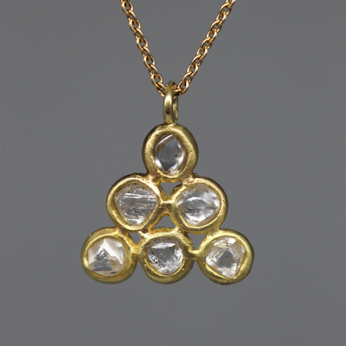 Gold necklace with a triangular pendant featuring clear gemstones on a dark gray background